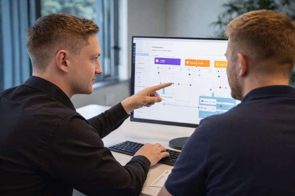 Scaile-udvikler sidder sammen med kundens operations-ansvarlige og gennemgår et automationsflow på en skærm.